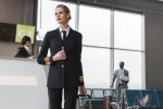 female pilot with suitcase at airport reception
